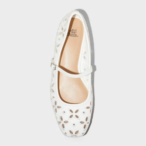 White flat shoe with floral cut-out design on a light gray background