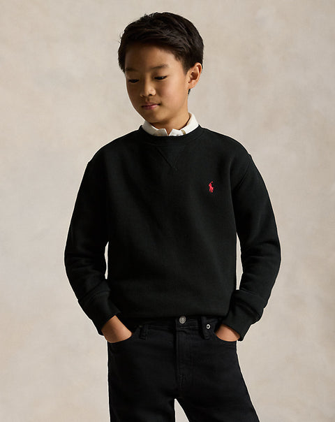 Child wearing a black sweater with a red logo on a beige background