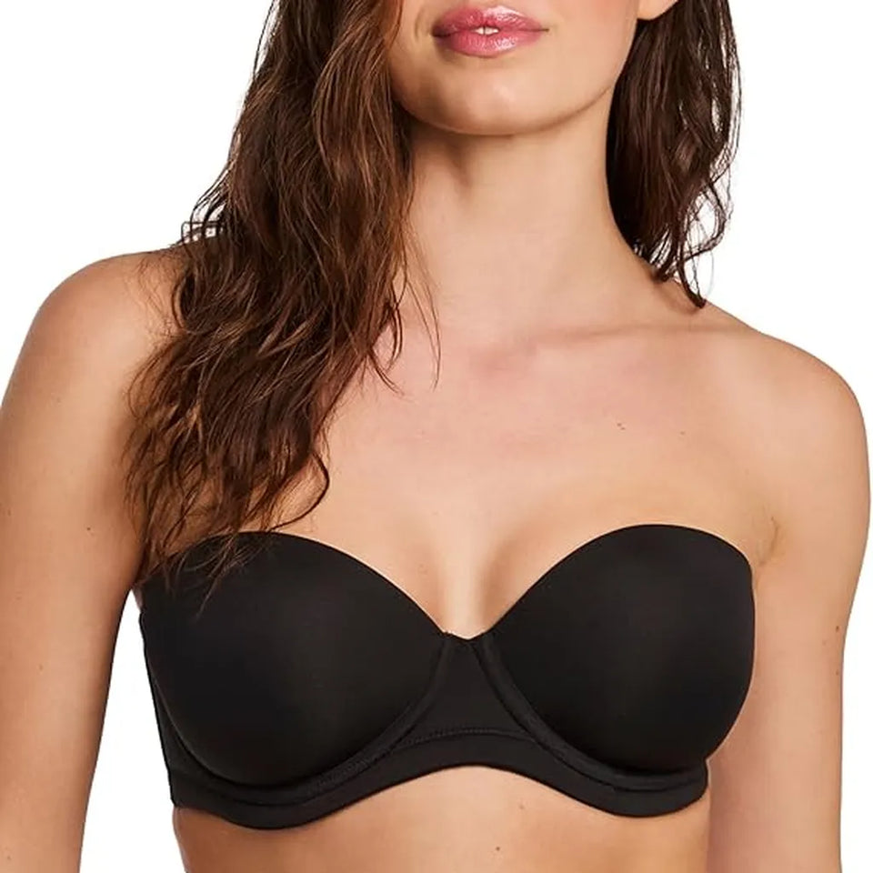 A close-up of a woman wearing a black strapless bandeau bra against a plain white background.