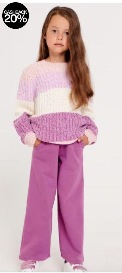 Young girl wearing a colorful sweater and purple pants on a white background