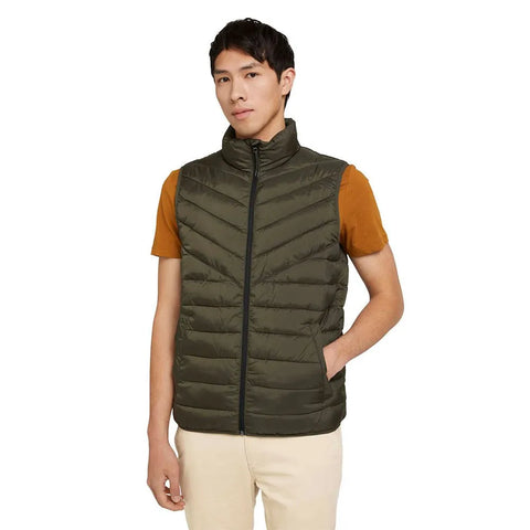 Man wearing a green puffer vest over a brown shirt on a white background