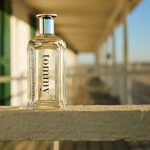 Clear glass bottle labeled 'tommy' on a stone ledge with a blurred background