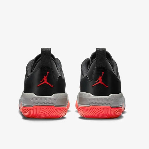 Black sneakers with red swoosh logo and red soles on a white background