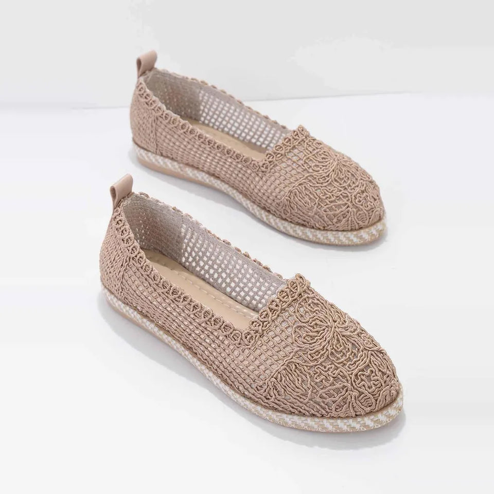 A pair of women's slip-on espadrille-style flats in a warm taupe-beige color, featuring a textured woven upper, openwork mesh arch support, and braided jute-wrapped soles, shown on a clean white background.
