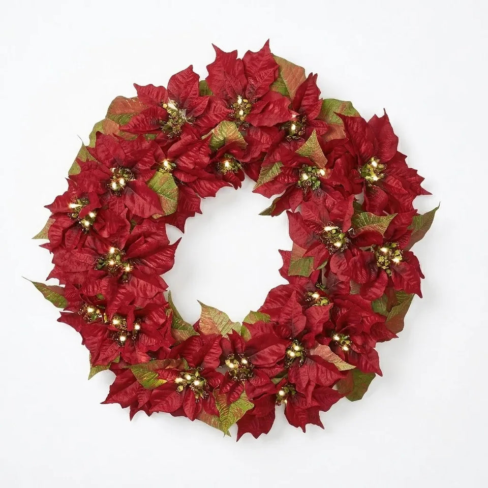 A festive artificial poinsettia wreath in deep red with metallic gold and olive green accents, photographed against a clean white background.