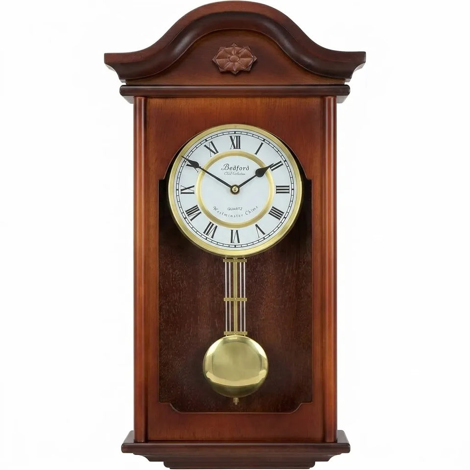 A traditional wooden wall clock with a polished mahogany brown case, a white clock face with black Roman numerals, gold hands and bezel, and a brass pendulum bob, shown against a plain white background.