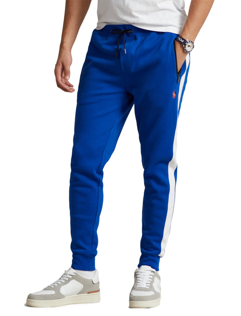 Blue jogger pants with a white stripe worn by a person on a white background